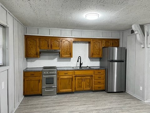view of a kitchen with a sink stove and fridge with wood cabinentry